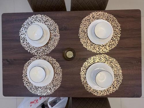 a wooden table with plates and bowls on it at Rawda 2 Bed-Room Apartment in Jeddah, 100 meter to supermarket in Jeddah