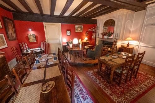 une salle à manger avec des murs rouges, une table et des chaises dans l'établissement Le Relais Cicero, à La Flèche