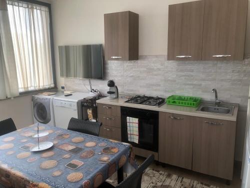 - une cuisine avec une table, une cuisinière et un évier dans l'établissement Appartamento Villa lucia, à SantʼEufemia Lamezia