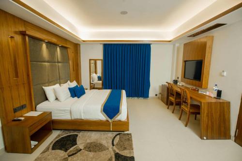 Schlafzimmer mit einem Bett, einem Schreibtisch und einem TV in der Unterkunft Roomsity Pride Delhi in Neu-Delhi