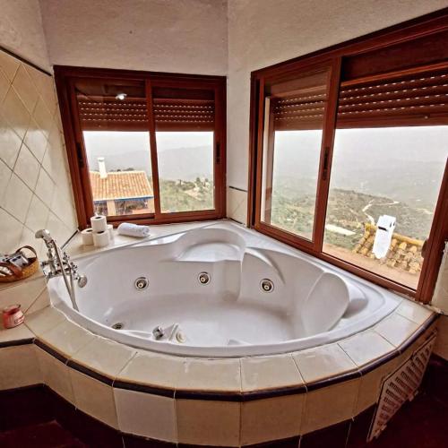 a large bath tub in a bathroom with two windows at Hotel Rural Verde Oliva in Comares