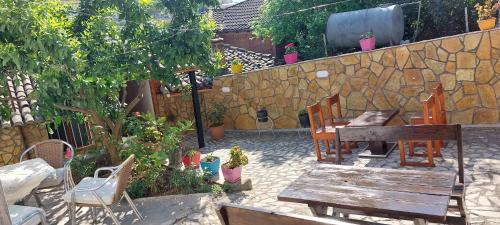 a patio with a table and chairs and a stone wall at Niku HomeStay in Berat