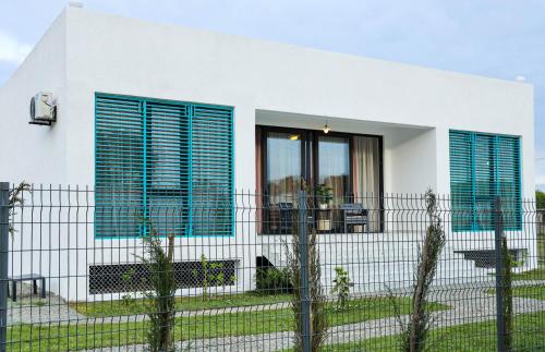 a white house with blue windows and a fence at Villa Capri-Kaprovani in Shekvetili