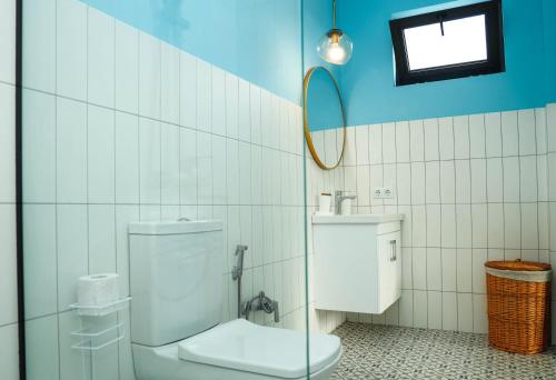 a white tiled bathroom with a toilet and a mirror at Villa Capri-Kaprovani in Shekvetili