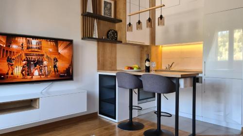 a kitchen with a tv and a bar with two stools at Marina City key Luxury Studio in Podgorica