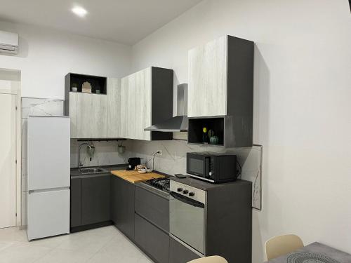 a kitchen with black and white cabinets and a microwave at Cherry rooms in La Spezia