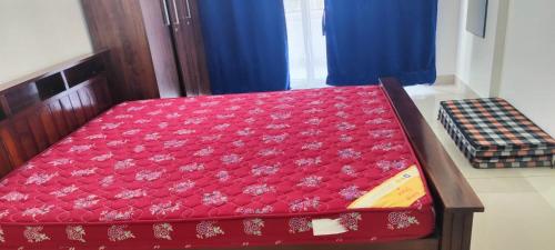 a bed with a red cover on top of it at Vandana Callisto in Mangalore