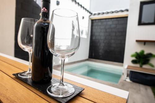 a bottle of wine and two wine glasses on a table at Jacuzzi Suite Paradise in Ciudad Real