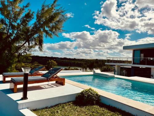 a swimming pool with two lounge chairs and a house at Villa Luasah in Vila Praia Do Bilene