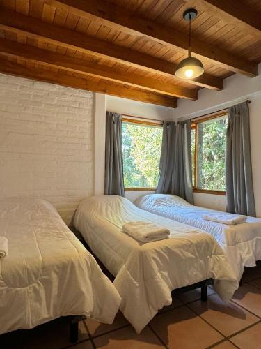 two beds in a room with two windows at Huilen de Bandurrias in San Martín de los Andes