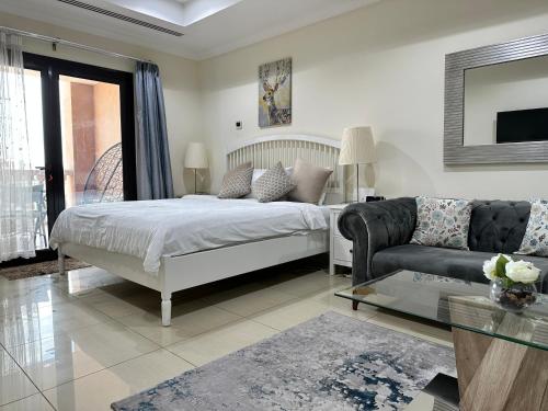 a white bedroom with a bed and a couch at Alken Studio - Amazing Superior Studio with Marvellous Marina View in the Pearl, Doha in Doha