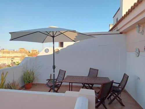 een tafel en stoelen met een parasol op een balkon bij ÁTICO RESIDENCIAL MARIANA parking privado y piscina in Rincón de la Victoria
