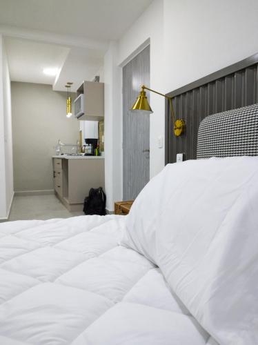 a bedroom with a white bed and a kitchen at WUER Expiatorio in León