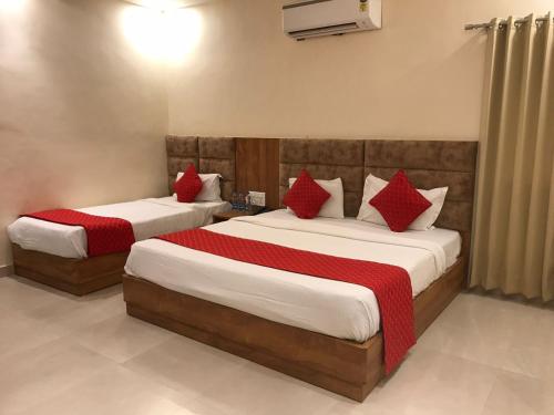 two beds in a hotel room with red pillows at Hampton Hotel - 100 mt from Golden Temple in Amritsar