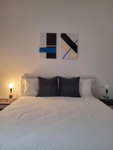 a bedroom with a white bed with two paintings on the wall at Arya Apartment in Torre Boldone