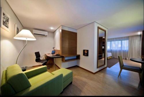 Apartamento Radisson Belém في بيليم: غرفة معيشة مع أريكة خضراء ومكتب