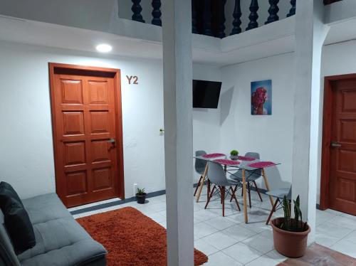 uma sala de estar com uma mesa e uma porta vermelha em Hospedaje San Benito em San Cristóbal de Las Casas