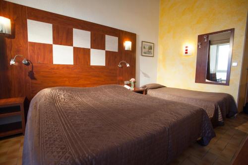a hotel room with two beds and a mirror at Hotel Les Dunes in Marseillan