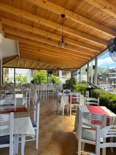 un ristorante con tavoli e sedie bianchi e soffitto in legno di Vila Spiro a Ksamil