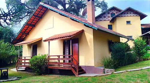 a small house with a porch and a balcony at Pousada Dona Elza in Monte Verde