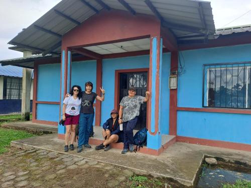 a group of people standing outside of a blue house at Hotel Turismo Asokilc in Limoncocha