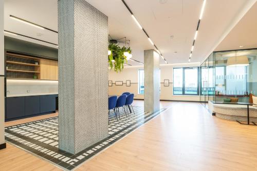an office lobby with blue chairs and columns at The Cornerstone Two by Dublin At Home in Dublin