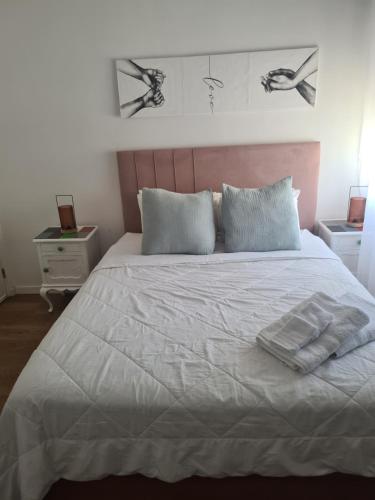 a bedroom with a white bed with two pillows at Quarto Santiago in Corroios