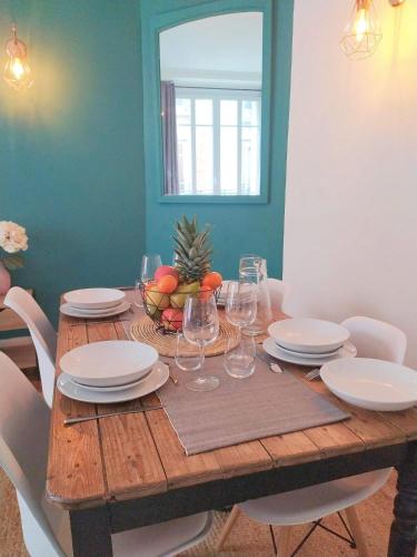 une table en bois avec des assiettes et des verres à vin dessus dans l'établissement Charmant appartement au pied d'un parc arboré, à Clichy