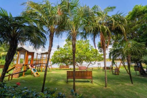 un parque con palmeras y un parque infantil con tobogán. en Condomínio Porto Smeralda, en Camassari