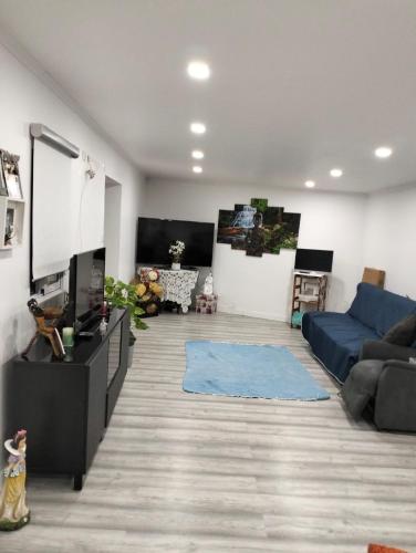 un soggiorno con un divano blu e una TV di Casa Alentejana a Mora