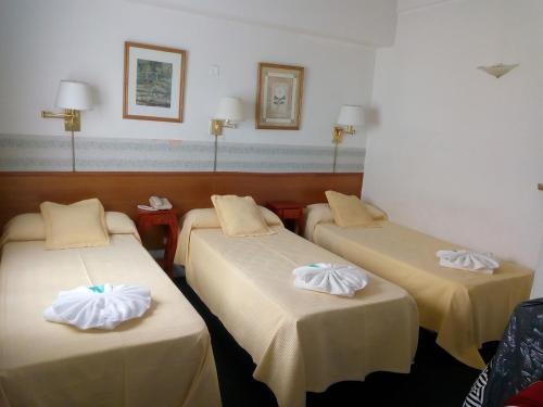 three beds in a hotel room with towels on them at Apolo Atlantis in Mar del Plata