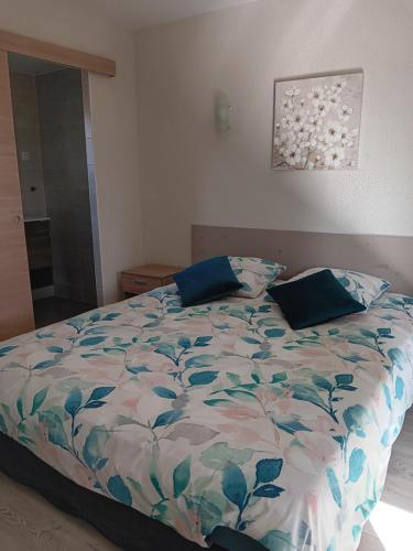 a bedroom with a bed with a floral comforter at Au Moulin du Comte - en gîte in Bourrouillan