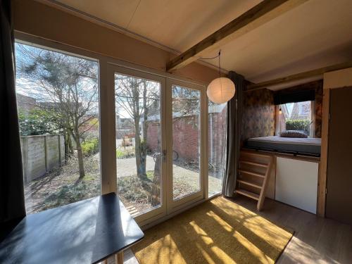 a small house with a large window and a bed at A tiny house close to nature - Amsterdam region in Lelystad