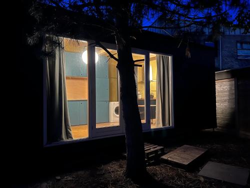 a window of a house with a tree in the dark at A tiny house - Amsterdam region in Lelystad