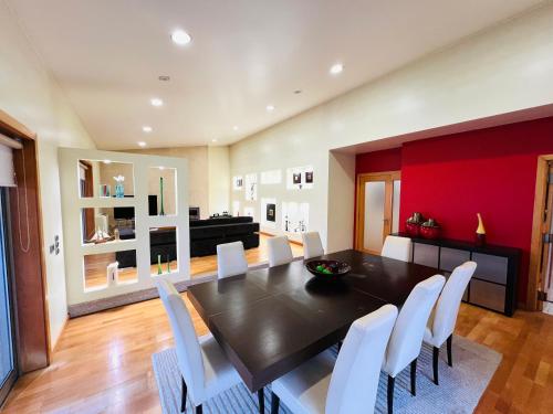 a dining room with a black table and white chairs at A Casa do Pai Carlos in Salreu