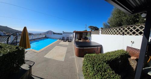 a backyard with a swimming pool next to a white fence at La Casita De Juani in Santa Maria de Guia de Gran Canaria