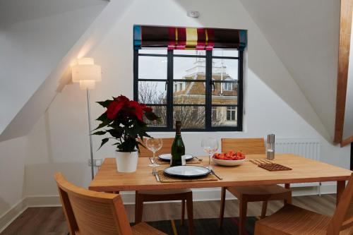 a dining room table with a bottle of wine and flowers at The Penthouse in King's Lynn