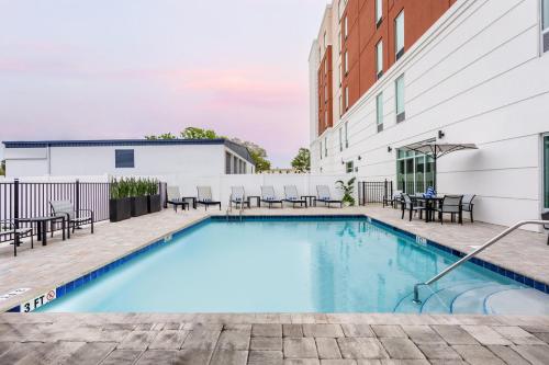 a swimming pool with tables and chairs next to a building at Staybridge Suites Winter Haven - Auburndale in Winter Haven