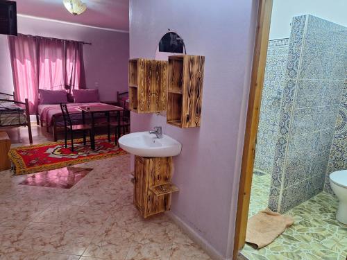 ein Badezimmer mit einem Waschbecken und ein Wohnzimmer in der Unterkunft Maison Touria in Ouzoud
