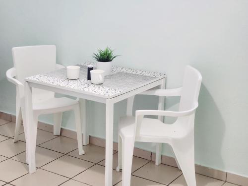 une table et des chaises blanches avec une plante. dans l'établissement PERLA in Carolina PR 11 Min From Airport, à Carolina