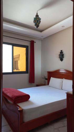 1 dormitorio con 1 cama blanca grande y ventana en Assia's appartement, en Essaouira