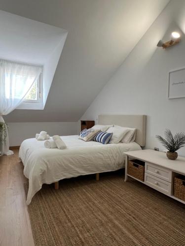 a white bedroom with a bed and a window at Pinares de Boo in Boó de Piélagos