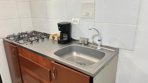 Líbano的住宿－Acogedor apartamento con Balcón 206，厨房柜台设有水槽和炉灶。
