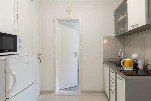a kitchen with white cabinets and a white door at Stephanie green island apartments in Šipanska Luka