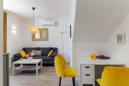a living room with a couch and a table and yellow chairs at Stephanie green island apartments in Šipanska Luka