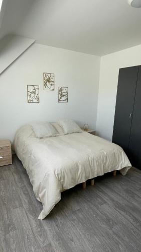 - une chambre blanche avec un lit et deux photos sur le mur dans l'établissement Maison - Réville avec son boulodrome !, à Réville