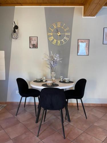 a table with chairs and a clock on a wall at Appartamento - Casa Usignolo in Castelletto sopra Ticino