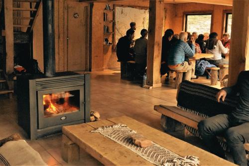 a living room with a fireplace and people sitting at tables at Puesto Cagliero - Refugio de montaña in El Chalten