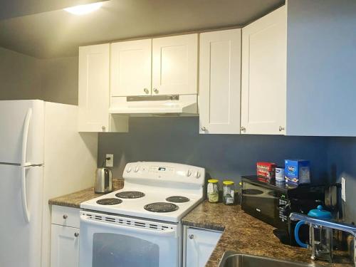 a kitchen with a white stove and white cabinets at Spacious Stylish Private 2-Bedroom Home in Barrie