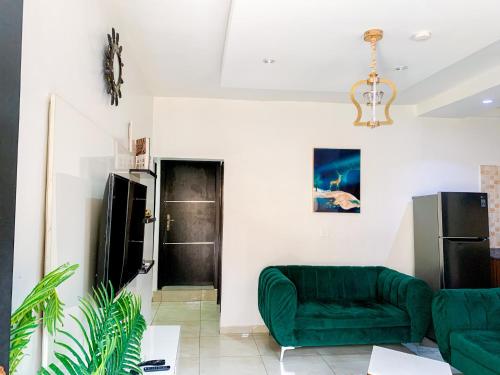 ein Wohnzimmer mit einem grünen Sofa und einem Kühlschrank in der Unterkunft Yardcourt 3Bedroom in Lagos